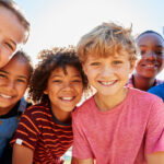 Smiling children gathered together looking at the camera. Raising confident kids image.