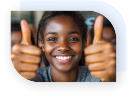 A young teen smiling and holding both hands up with a thumbs up signal.
